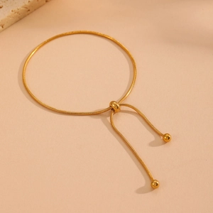 Detail of adjustable gold snake chain bracelet with sliding clasp and gold beads
