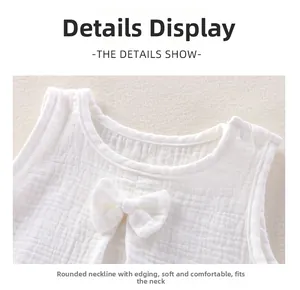 Détail du haut en gaze de coton blanc pour bébé avec nœud et épaule à bouton-pression