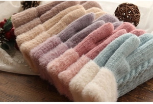 Detail of warm knitted gloves with plush faux fur cuffs in various soft winter colors