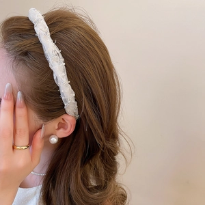 Detail of elegant cream lace headband with sparkling rhinestones and pearls on wavy hair