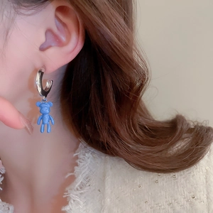 Close-up of blue flocked bear earring worn on ear showing elegant size and texture