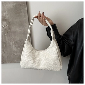 Detail shot of white faux crocodile texture on a minimalist fashion underarm bag
