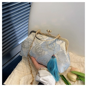 Detail of light blue shell bag with rose embroidery, gold clasp, and elegant blue tassel