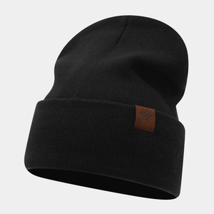 Close-up of the knitted texture and brown leather snowflake patch on a black beanie