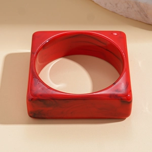 Macro shot of red marbled resin square bracelet on textured stone aesthetic background