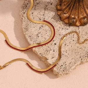 Macro detail of gold-plated herringbone chain with red zircon stones and lobster clasp