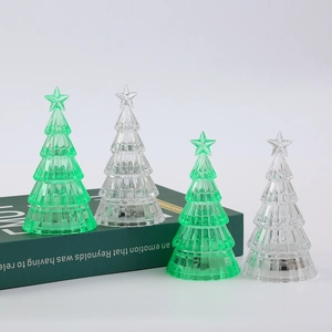 Close-up of crystal glass Christmas trees with star toppers on a green book surface