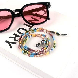 Detail of colorful woven bohemian eyewear strap with rubber loops on a white book