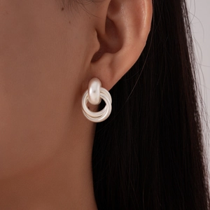 Détail de boucles d'oreilles argentées mates à trois anneaux portées à l'oreille