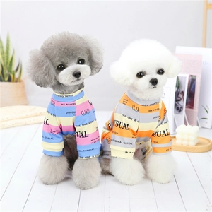 Detail of blue and orange striped cotton pet pajamas for small dogs in a cozy home setting