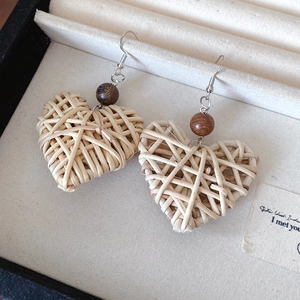 Detail of heart-shaped rattan earrings with dark wooden beads in a jewelry box