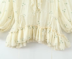 Dettaglio ricamo floreale su abito in chiffon giallo con scollo a V e volant
