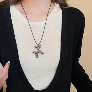 Detailed view of leopard print balloon dog charm necklace on model wearing black cardigan