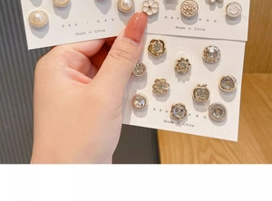 Close-up of pearl and flower pins on card packaging with metallic and gem accents