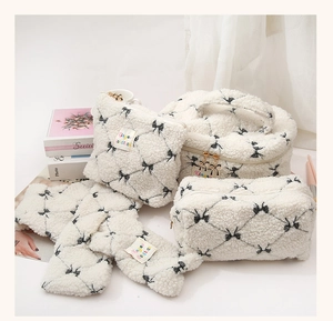 Detail set of white faux shearling cosmetic bags with black bow patterns and gold zippers