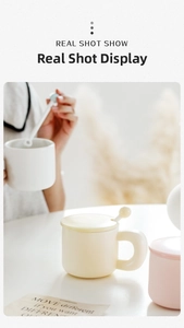 Close-up of cream ceramic mug set with lid, matching spoon, and rounded handle