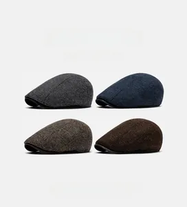 Detail view of four classic woolen newsboy caps in gray, blue, brown and tan herringbone