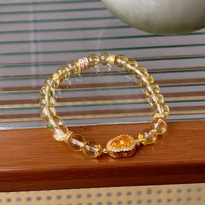 Detailansicht eines Citrin-Kürbis-Armbands mit Zirkonia-Herz auf Holzoberfläche