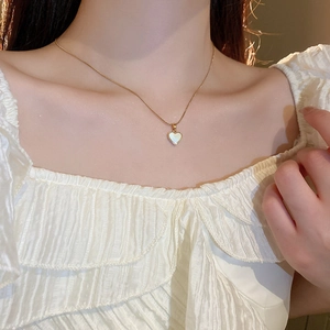 Gros plan d'un collier pendentif coeur doré avec nacre sur le cou d'un mannequin femme