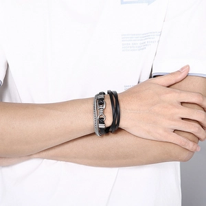 Close-up of men's layered leather and steel bracelets featuring horsebit metal detail