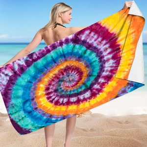 Colorful tie-dye microfiber beach towel with vibrant spiral pattern shown on sunny beach