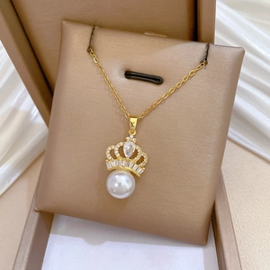 Detailed close-up of a golden crown pearl pendant necklace inside a jewelry gift box