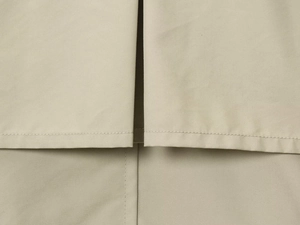 Close-up of the side slit hem and fine stitching on a khaki water-resistant windbreaker