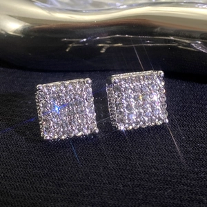 Detalle macro de pendientes de botón cuadrados plateados con circonitas brillantes