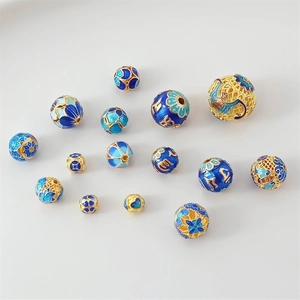 Detailed view of handmade cloisonne enamel beads with gold trim and blue floral patterns