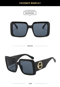 Detail of square black sunglasses with wide temples and golden chain-link metal accents