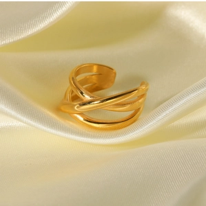 Detail of 18K gold-plated multi-layer crisscross ring on elegant cream silk fabric
