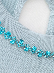Macro view of blue rhinestones on light blue knitted fabric with teardrop back detail