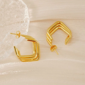 Detail view of gold triple layered square hoop earrings on elegant silk fabric