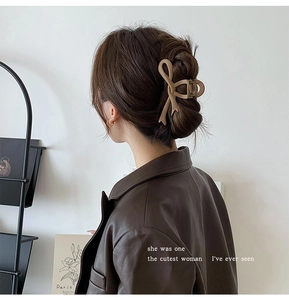 Close-up of a matte beige bow hair claw clip styled on a woman's back bun hairstyle