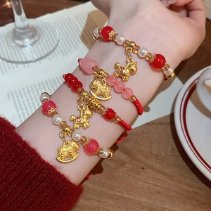 Gros plan de bracelets tressés en cordon rouge avec pendentifs cheval sur le poignet