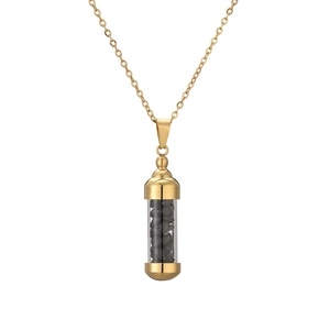 Close-up of golden capsule perfume bottle pendant with black crushed stones on chain