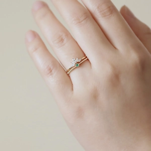 Detail of s925 silver crown ring and green gemstone stackable bands in gold finish