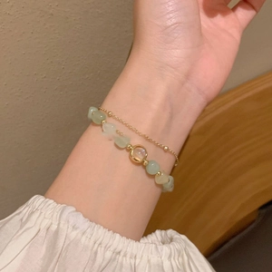 Double-layer gold bracelet with light green natural stones and circular metal charm detail