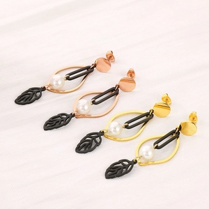 Orecchini a foglia in oro rosa e oro con perle bianche su sfondo di tessuto bianco