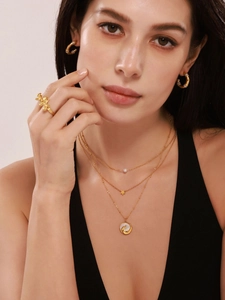 Close-up of gold-plated phoenix shell pendant necklace with pearl and star details