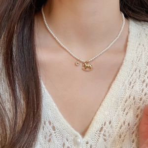 Close-up of a zircon horse pearl necklace on a model with golden pendants