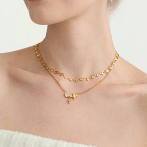 Nahaufnahme einer zweilagigen goldenen Halskette mit Herzanhängern und einem Kreuzanhänger