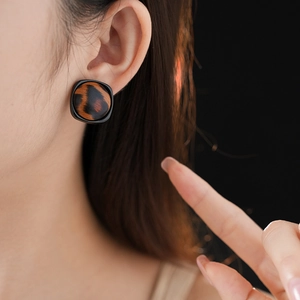Gros plan d'une boucle d'oreille léopard avec cadre carré noir portée par le modèle