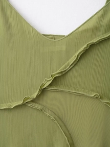 Dettaglio del tessuto plissettato verde muschio con volant su un vestito da vacanza