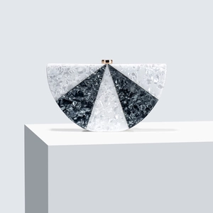Detailed macro of semi-circular acrylic clutch with black and white marble pattern and gold clasp