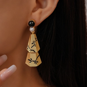 Close-up of vintage tassel earrings with pearls and geometric branch patterns on a model