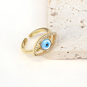 Detail of golden Evil Eye ring with blue stone and white zircons on a stone surface