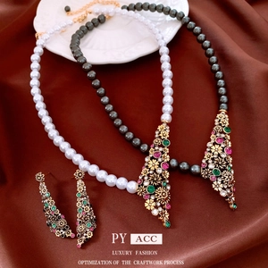 Set di gioielli vintage con collane di perle e orecchini floreali su tessuto marrone