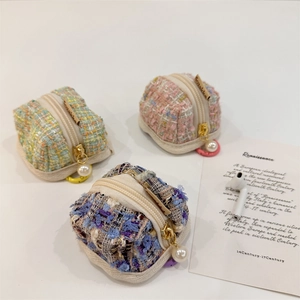 Three tweed AirPods storage cases in pastel colors with pearl zipper charms and earbuds