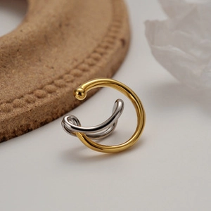 Detail of minimalist two-tone silver and 18K gold-plated intertwined geometric earrings